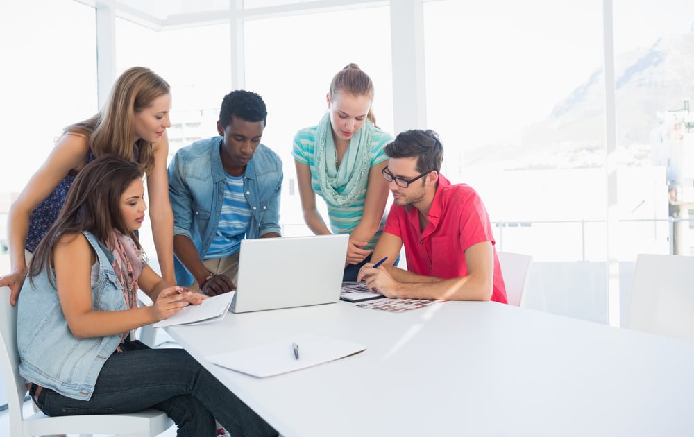 Group of young casual people using laptop in a bright office
