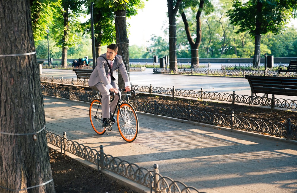 Handsome businessman riding bicycle to work in park